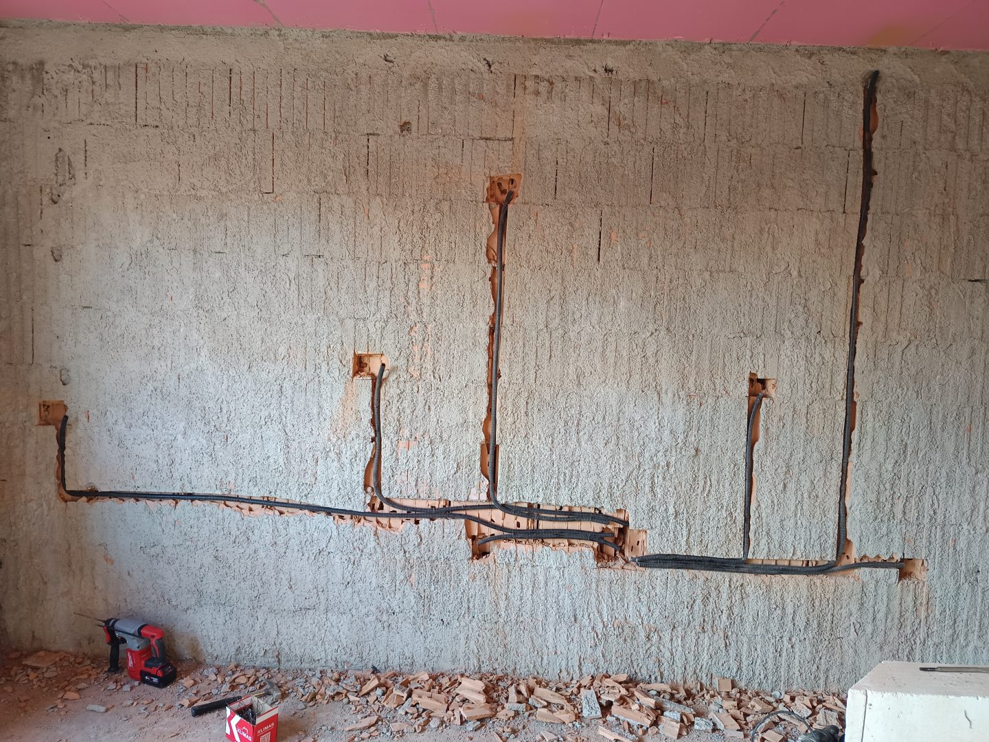 Trasee copex negru in canale pe perete de beton si doze montate
